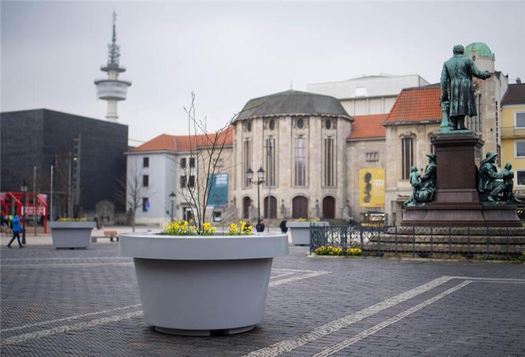 Ein grauer Kübel ist auf einem öffentlichen Platz zu sehen. 