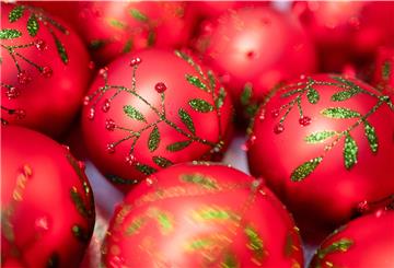 Roter Christbaumschmuck mit grünem Glitzer liegt nebeneinander auf dem Tisch. 
