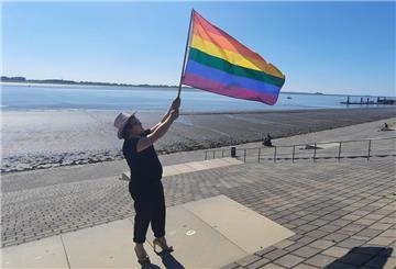 Eine Person hält eine Regenbogenflagge in die Luft