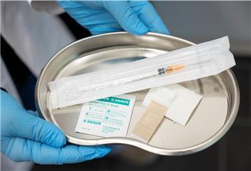 Eine Apothekerin steht mit Impfutensilien in einem Impfzimmer in der Apotheke.