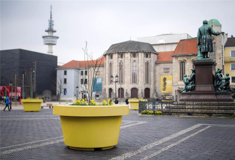 Ein gelber Kübel ist auf einem öffentlichen Platz zu sehen. 