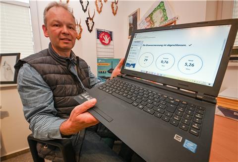 Ein Mann hält seinen Laptop in die Kamera.