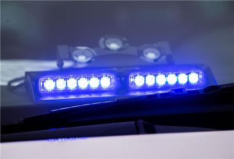 Ein Blaulicht leuchtet unter der Frontscheibe eines Einsatzfahrzeugs der Polizei.