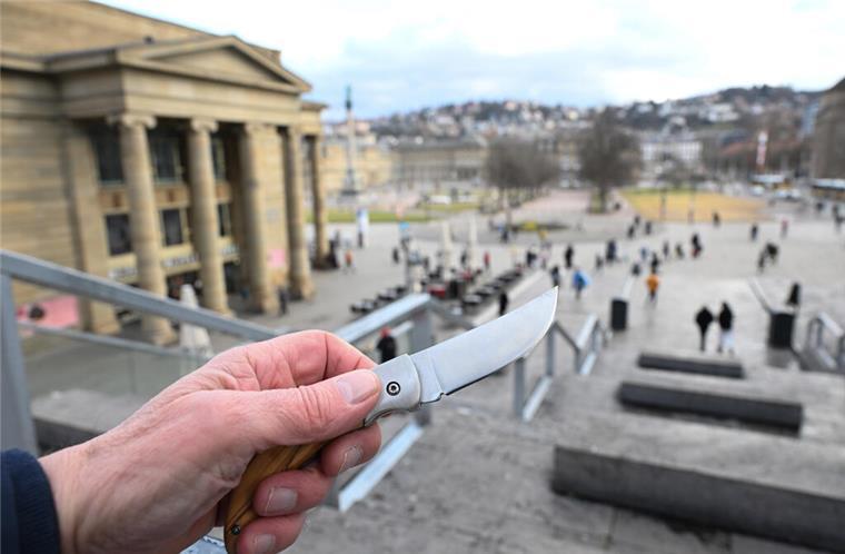  Eine Hand hält ein Messer in der Hand (gestellte Szene), im Hintergrund der Schlossplatz.  In mehreren Großstadtbahnhöfen gilt ab Mai 2025 ein verlängertes Verbot für Waffen und Messer.