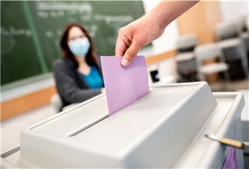Ein Wähler wirft in einem Wahllokal, das im Klassenraum einer Schule untergebracht ist, seinen Stimmzettel für die Kommunalwahl in die Wahlurne.