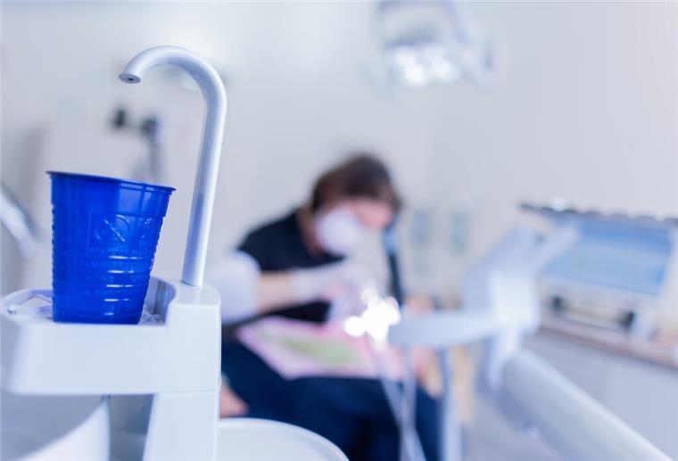 Eine Zahnarzthelferin führt an einer Patientin eine Zahnreinigung durch.