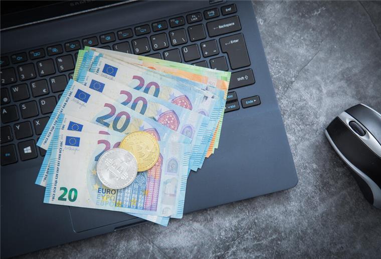 Geld liegt auf einem Laptop. In volatilen Börsenzeiten prüfen viele Anleger einen Depotwechsel – der richtige Zeitpunkt kann entscheidend sein. Ein Vergleich der Anbieter spart oft bares Geld.