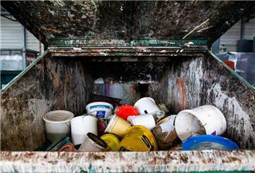 Alte Farbeimer liegen in einem Container auf dem Gelände eines Recyclinghofs. In welchen Müll gehören alte Farbreste? Darf man sie im Restmüll entsorgen oder gehören sie auf den Wertstoffhof. Die Antwort überrascht.
