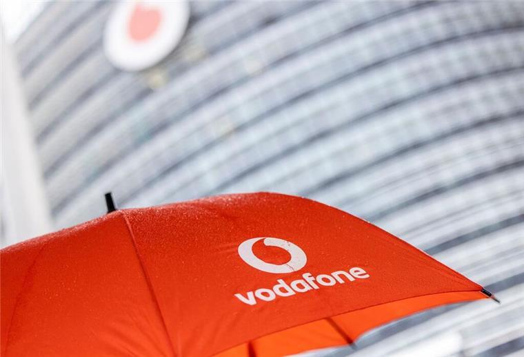 Internet wird teurer! Zwei große Anbieter erhöhen die Preise spürbar Ein Passant geht mit einem aufgespanntem Regenschirm mit dem Logo von Vodafone an der Konzernzentrale vorbei.
