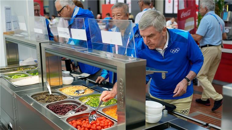 IOC-Präsident Thomas Bach (r) testete auch das Essen im olympischen Dorf.