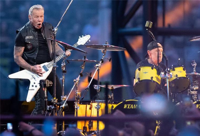 Metallica gibt 2026 drei Konzerte in Deutschland James Hetfield (l), Sänger und Gitarrist, und Lars Ulrich, Schlagzeuger, von der US-Metal-Band Metallica stehen im Münchner Olympiastadion auf der Bühne.