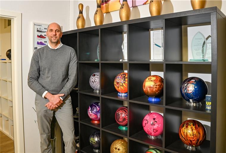 Ein Mann steht vor einem Regal mit Bowlingkugeln.