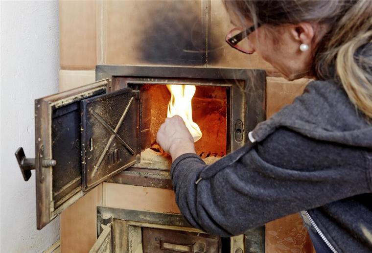 Eine Frau legt Holz in einen brennenden Kamin.