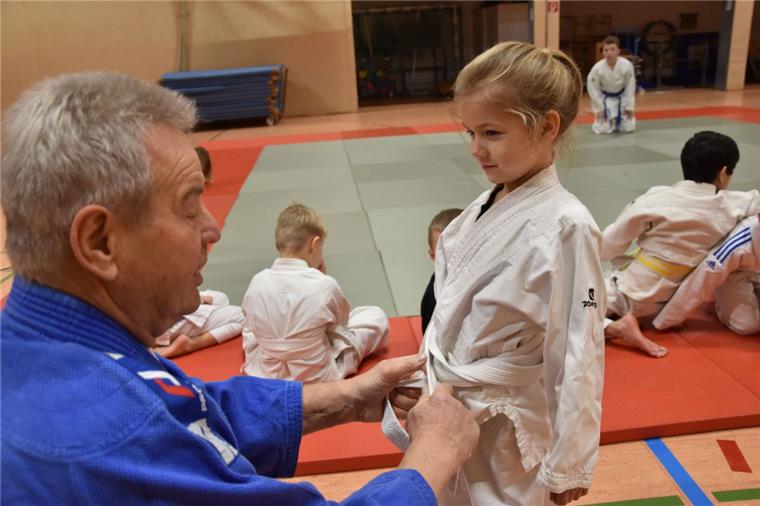 Judo-Trainer Eckhard Lehmann zurrt den Knoten von Jolins Gurt sorgfältig fest, bevor die Sportstunde losgeht. Foto: Rendelsmann