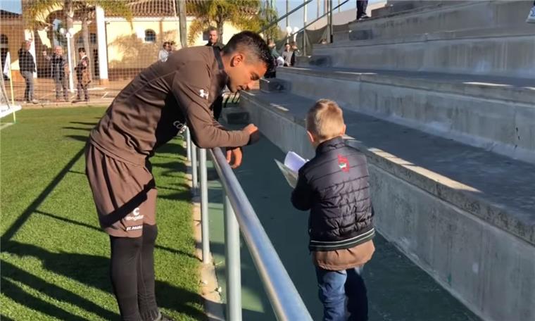 Justus Engel aus Düring zeigt einem Spieler des Fußball-Zweitligisten FC St. Pauli sein Malbuch.