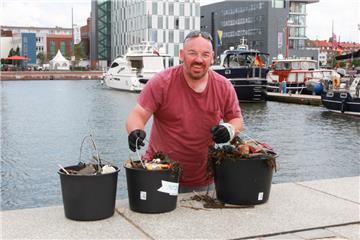 Kai Helms bringt beim Bremerhavener Hafenputz Eimer voller ekliger Beute aus dem Hafenbecken.