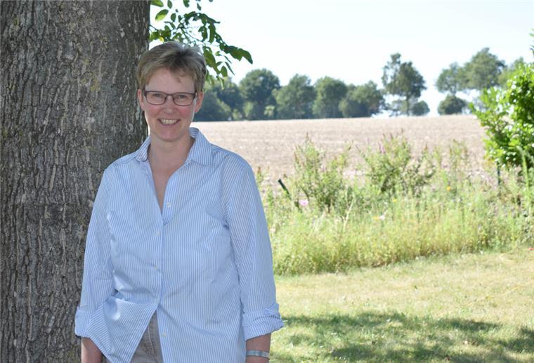 Kerstin Thies, Vorsitzende der Heeslinger Heimat- und Fördergemeinschaft, steht vor einem Baum und lächelt.