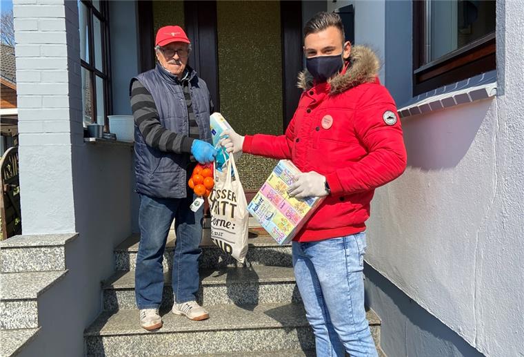 Netzwerk „Bremerhaven bleibt gesund“ wächst rasant Kim-Jura Kargoscha überreicht Einkäufe an einen älteren Herrn.