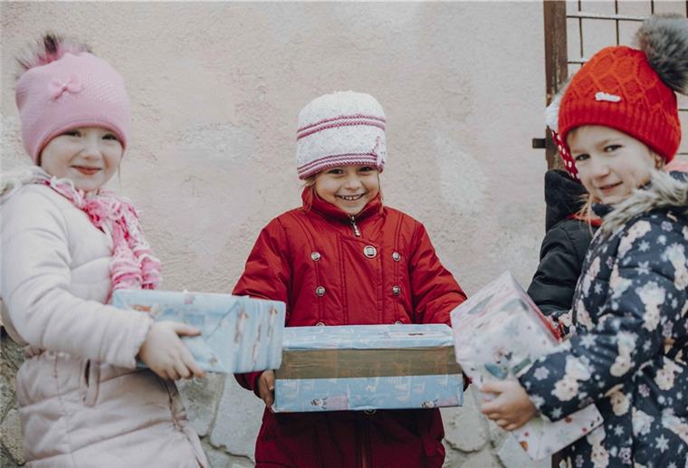 Kinder aus Osteuropa halten mit strahlenden Augen stolz ihr Weihnachtsgeschenk fest. 