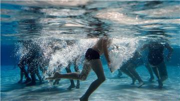 Kinder spielen im Becken eines Freibads.