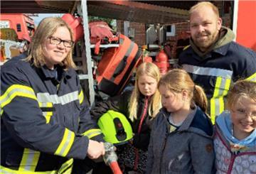  Kinderfeuerwehrwartin Tina Bock-Horning und ihr Stellvertreter Sören Marten zeigen den Kindern die Ausrüstung der Feuerwehr.  