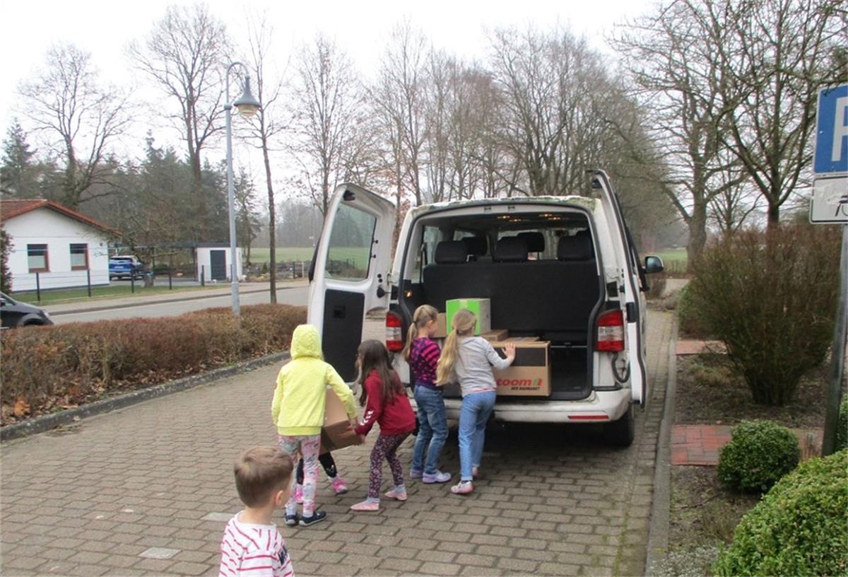 Das Foto zeigt, wie Kinder Pakete in einen Bus bringen. 