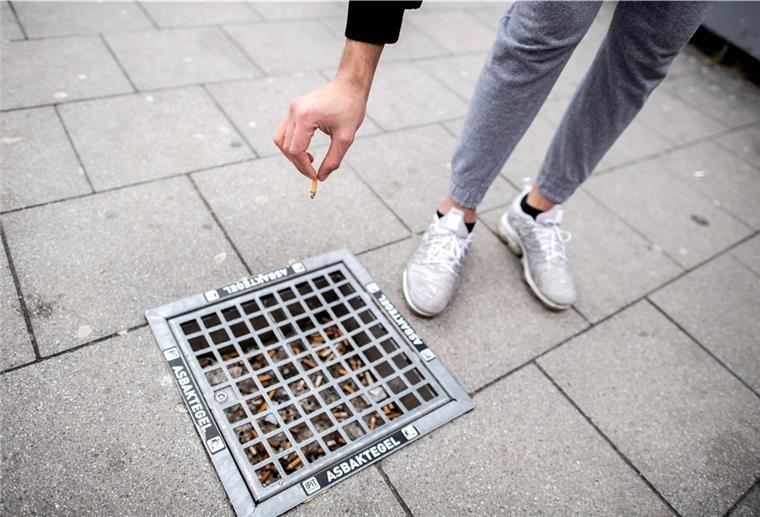 Ein Mann wirft einen Zigarettenstummel in einen Bodenaschenbecher in der Oldenburger Innenstadt.