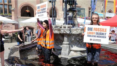 Klima-Aktivisten der Gruppe „Letzte Generation“ stehen zum Auftakt der Klimaschutztage im Gänseliesel-Brunnen.