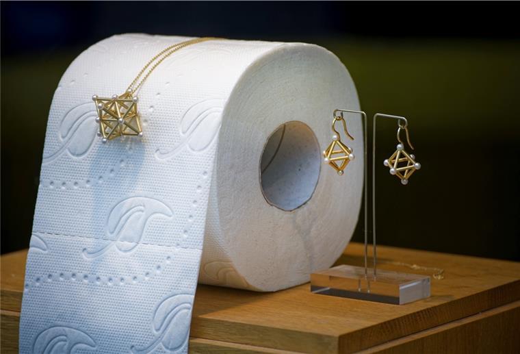 Klopapier wird deutlich teurer Eine Kette und Ohrhänger sind neben einer Rolle Klopapier im Schaufenster einer Goldschmiede ausgestellt.