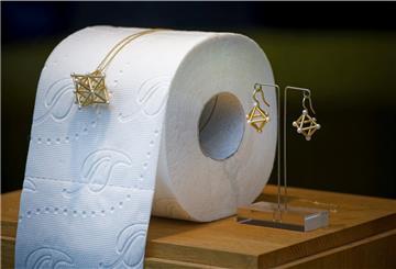 Eine Kette und Ohrhänger sind neben einer Rolle Klopapier im Schaufenster einer Goldschmiede ausgestellt. 
