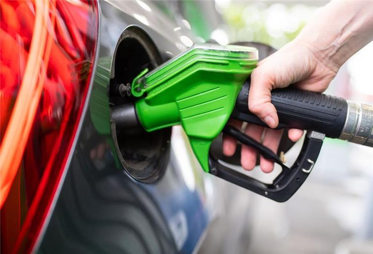 Mit diesen einfachen Tricks beim Tanken Geld sparen Eine Frau hält an einer Tankstelle an einer Zapfsäule eine Zapfpistole in der Hand und betankt ein Auto.