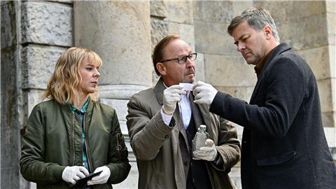 Kommissare Angelika Flierl (Bernadette Heerwagen, l-r), Ludwig Schaller (Alexander Held) und Harald Neuhauser (Marcus Mittermeier) inspizieren einen Tatort in einer Szene des Krimis „München Mord - A saisonale G`schicht“.