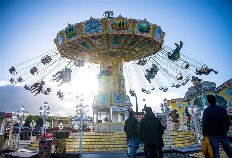 Bremer Freimarkt: Schausteller kämpfen mit Dreifachkrise Besucher des Bremer Freimarkts sitzen im Kettenkarussell. Davor stehen andere Besucher und schauen zu.