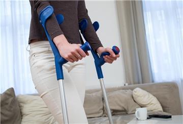 Eine Frau läuft mit Gehhilfen zu Hause. Krankengeld ist eine wichtige Absicherung bei längerer Krankheit. Wer Anspruch hat, sollte lückenlos die Arbeitsunfähigkeit nachweisen.