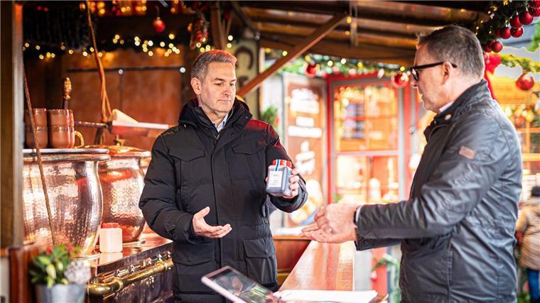 Kröning (l.) übergibt eine Probe Feuerzangenbowle an den Lebensmittelkontrolleur der Stadt Hannover, Thomas Rautenberg.