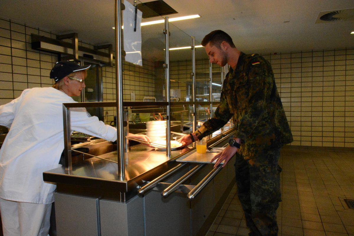 Küchenhilfskraft Sabine Schneider reicht Marineflieger Nico Henstra das aktuelle Mittagsgericht. Der junge Soldat ist zufrieden mit der Verpflegung vor Ort.