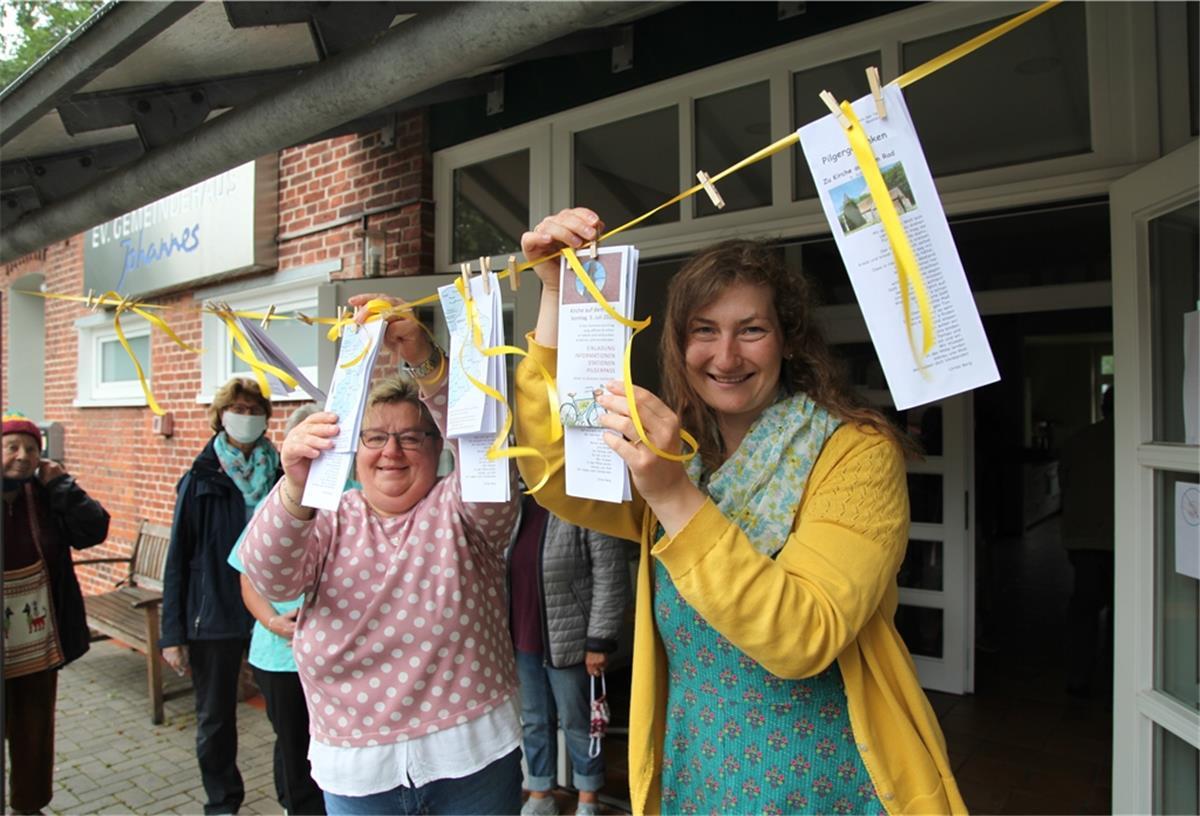 Kirche auf dem Rad: „Überrascht, wie viele dabei sind“ Küsterin Silvia Pauper und Pastorin Lara Schilde haben die Pilgerpässe vor dem Gemeindehaus in Bexhövede an einer Wäscheleine befestigt.