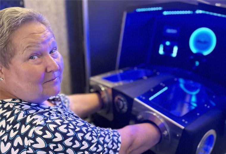 Eine ältere Dame hält ihre Hände in eine Maschine
