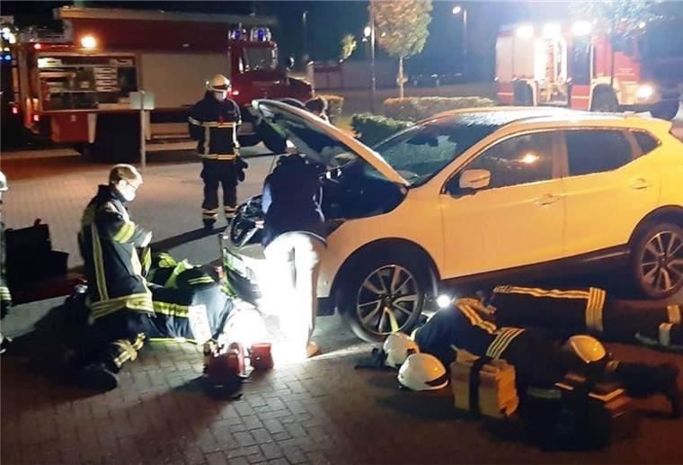 Feuerwehrleute arbeiten an und unter einem Auto.