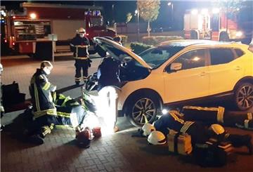 Feuerwehrleute arbeiten an und unter einem Auto.