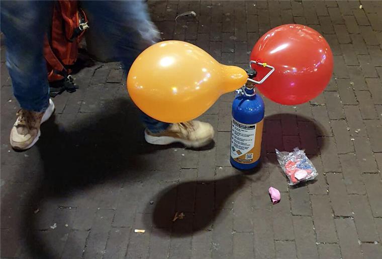 Lachgas: Regierung will Party-Droge verbieten 13.11.2024, Hamburg: ILLUSTRATION - Ein Mitarbeiter hält eine Tüte mit Luftballons neben drei Dosen Lachgas und einem Mundstück (weiß) am Tresen eines Kiosks. Der Umgang mit Lachgas als Partydroge besonders bei jungen Leuten könnte in Deutschland bald verboten werden. Das Bundeskabinett billigte dazu einen Entwurf von Gesundheitsminister Lauterbach (SPD), der auch ein Abgabeverbot über Automaten und Spätkaufläden vorsieht. Foto: Marcus Brandt/dpa +++ dpa-Bildfunk +++