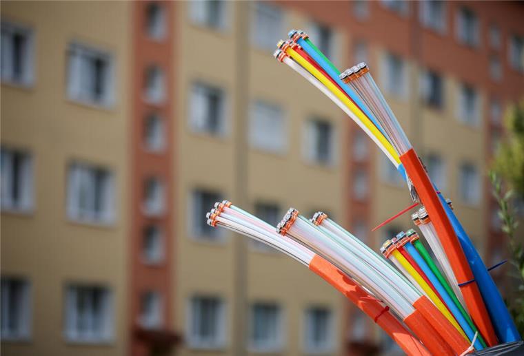 Kostenfalle Glasfaser - so schützt ihr euch vor unnötigen Zusatzkosten Aus dem Sockel eines Schaltschranks ragen Glasfaserkabel heraus.
