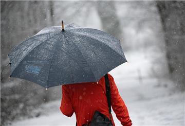  Eine Frau geht mit Regenschirm durch den Schnee. 