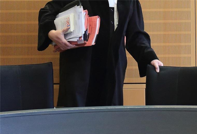 Ein Richter rückt sich in einem Verhandlungssaal seinen Stuhl zurecht.