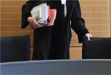 Ein Richter rückt sich in einem Verhandlungssaal seinen Stuhl zurecht.