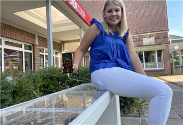Leonie Näth, Auszubildende bei der Stadt Geestland, hat schon Probe gesessen: An der neuen Solarbank im Langener Lindenhof kann man ab sofort sein Handy laden - ganz einfach per USB oder Induktion.