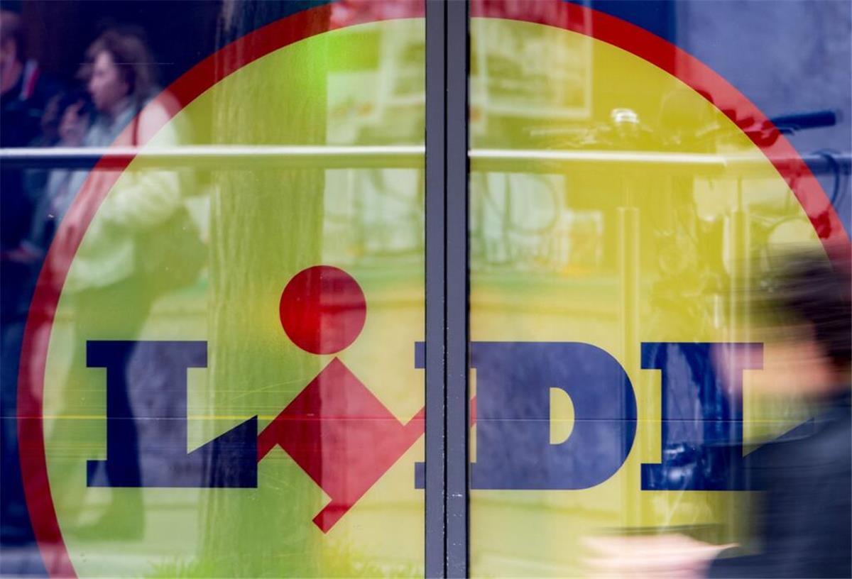 Lidl überrascht Kunden und eröffnet Filiale ganz ohne Lebensmittel! Eine Passantin geht am Eingang einer Lidl-Filiale vorbei.