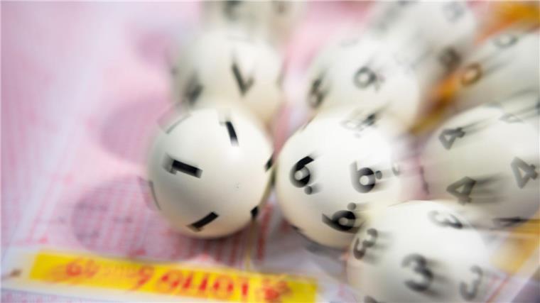Glückspilz knackt Jackpot: Millionen im Spiel 77 gewonnen Lotto-Kugeln liegen auf einem Lottoschein.