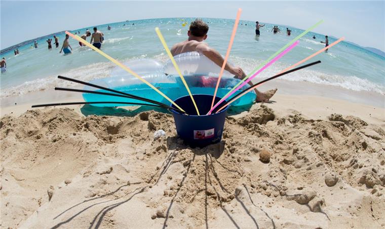 Ein Eimer mit Strohhalmen steht am Strand von Arenal auf Mallorca.