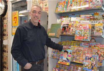 Ein Mann steht vor einem Magazin-Regal